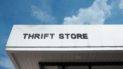 Thrift Store word signage on a retail or commercial building under a blue sky, symbolizing used goods, affordability, vintage, charity, sustainable shopping, secondhand, and community reuse