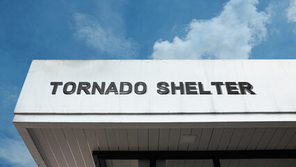 Tornado Shelter word signage on a fortified safety building under a blue sky, symbolizing emergency preparedness, severe weather, storm protection, safe room, crisis planning, and resilience