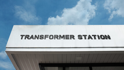 Fototapeta premium Transformer Station word signage on an electrical infrastructure building under a blue sky, symbolizing power grid, energy, electricity distribution, voltage conversion, industrial, and utility servic