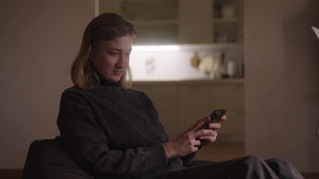 Young woman with cerebral palsy holding using smartphone at home, sitting in cozy atmosphere, enjoying online communication and leisure time, connecting with friends and family, slow motion.