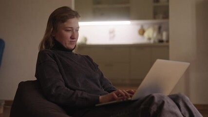 Woman with cerebral palsy experiencing wrist pain while working from home, using laptop in relaxed domestic setting, managing discomfort during daily tasks. Concept of knowledge, diversity, DEI.