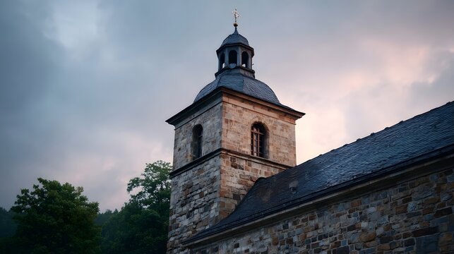 A weathered stone church tower with a steeple against a dramatic cloudy sky at dusk - Powered by Adobe