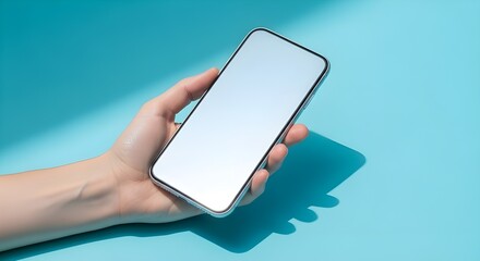 Las manos de una mujer sostienen con gracia un tel&eacute;fono inteligente contra un fondo azul suave.