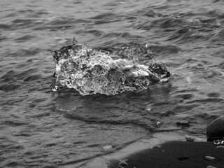 block of ice on black and volcanic sand