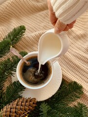 Cup of coffee and fir branches on a knitted background. Christmas still life aesthetic