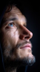 Obraz premium Close-up portrait of a mature man with a beard wearing a hood. He is looking up with a thoughtful expression on his face