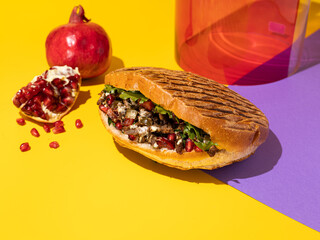 Colorful food photography, bright color food image. Tasty meat beef shawarma with vegetables, pomegranate and sauce in a pita bread on bright yellow and violet background