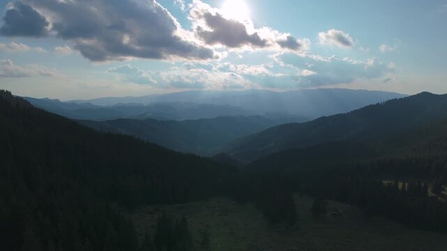 Spectacular aerial view over the lower Gaura Valley towards Simon village, with dramatic sun rays and distant Piatra Craiului mountains in the Carpathians, Romania