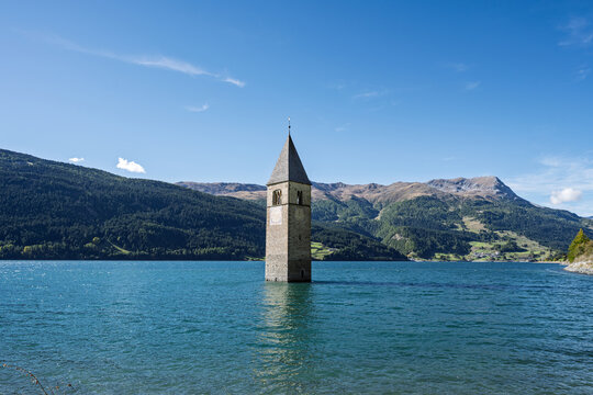Old gray church tower rising from the Reschensee lake, iconic landmark at Reschen Pass, Vinschgau, Italy