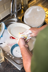 A man washing dishes in the kitchen, home chores, daily routine