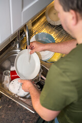A man washing dishes in the kitchen, home chores, daily routine
