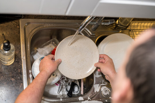 A man washing dishes in the kitchen, home chores, daily routine