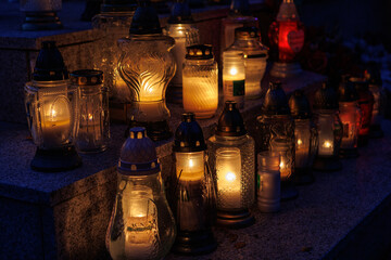 Nastrojowe ujęcie cmentarza po zmroku, gdzie jedynym źródłem światła są palące się znicze. Migoczące płomienie tworzą ciepłą, melancholijną atmosferę, podkreślając duchowy i refleksyjny wymiar miejsca © Michał.S-FOTO