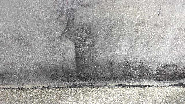 Slow motion shot of bitumen waterproofing panels and joint near facade and terrace edge, showing material structure and protective sealing layers