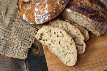 Sourdough bread and slices, fresh from the oven, with a crispy, smoky top and a side of starter