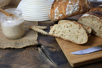 Sourdough bread and slices, fresh from the oven, with a crispy, smoky top and a side of starter