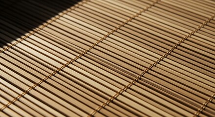 Closeup of a light brown bamboo mat with parallel slats a diagonal shadow and woven string