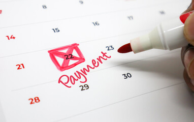 Close up of a hand highlighting an important payment due date on a calendar, emphasizing financial organization and timely bill management