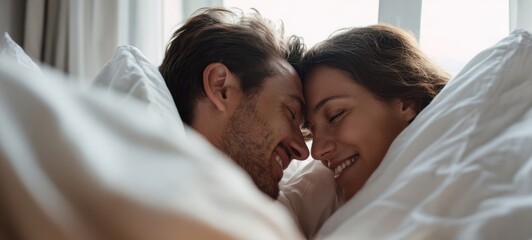 The couple sharing an intimate morning cuddle under white sheets in a sunlit bedroom
