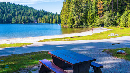 Picnic table near empty beach at Sasamat Lake, BC, Canada.