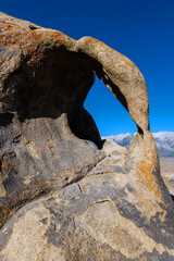 Cyclops Arch Framing the Blue Sky and Snowy Mountains. Alabama Hills, California.