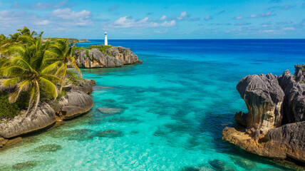 Aerial view of a tropical coastline with turquoise water, rocky cliffs, and a lighthouse