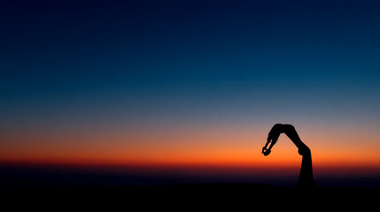 Silhouette of a person performing a yoga pose against a vibrant sunset sky orange