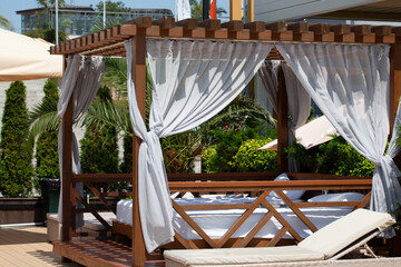White beach canopy. Luxury beach tents with white curtains at the resort. Summer vacation concept. Beach bungalows in Sochi, Mandarin Beach, Adler, Russia