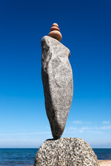 A tall pyramid of multicolored stones against the background of the sea and the blue sky
