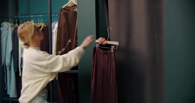 Assistant handing clothes into fitting room