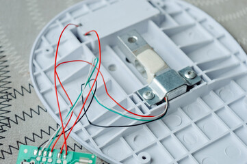 Disassembled electronic device kitchen scales with circuit board wires plastic parts on a table.Useful for articles about electronics repair, DIY projects, device maintenance and engineering tutorials