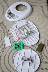 Disassembled electronic device kitchen scales with circuit board wires plastic parts on a table.Useful for articles about electronics repair, DIY projects, device maintenance and engineering tutorials