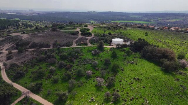 Aerial 4K footage of Ben Shemen Forest in central Israel, featuring the iconic &ldquo;Chinese House&rdquo; structure surrounded by dense Mediterranean woodland. The drone captures sweeping views of green pine tre