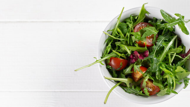 Fresh Arugula and Tomato Salad in a White Bowl on Rustic White Wooden Background - Powered by Adobe