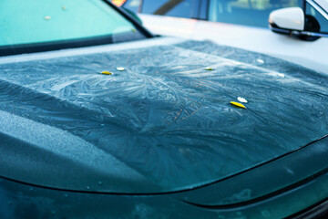 Frost on the hood of a parked car. Frozen car outside on the street in winter.