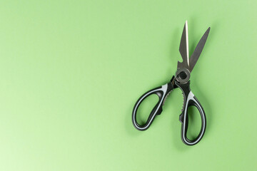 Black Kitchen Scissors on Vibrant Green Background: Top View Minimalist Stock Photo