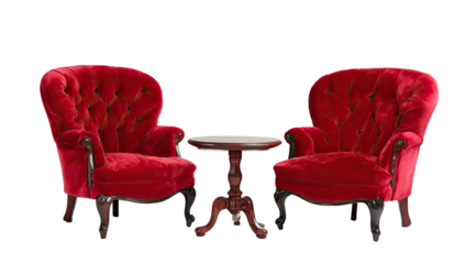 Two ornate red velvet armchairs and a small wooden side table set against a black backdrop