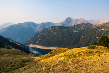 Fototapeta premium Low water level of Lac de l’Oule at sunrise, seen from a hiking trail between Col de Portet and Refuge du Bastan