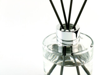 luxury aroma scented reed diffuser glass bottle with black sticks on white table and white wall background in nice living room which can create cozy relax aroma ambient scent in from room freshener