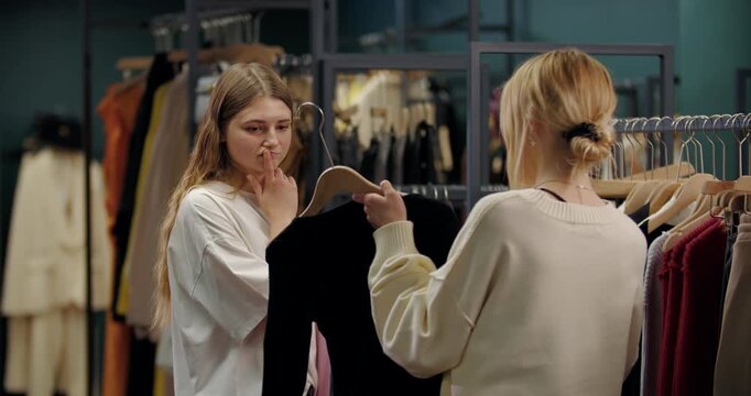 Woman thoughtfully choosing outfit in fashion store
