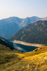 Obraz premium Low water level of Lac de l’Oule at sunrise, seen from a hiking trail between Col de Portet and Refuge du Bastan