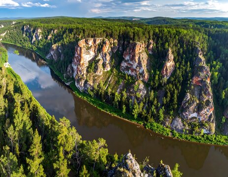 Aerial view of a winding river surrounded by lush green forests and striking reddish-brown rock formations