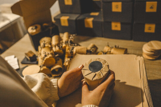 Hands carefully wrapping a gift with brown paper, creating a rustic aesthetic