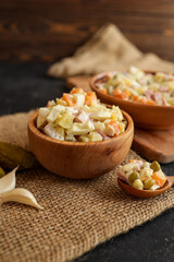 Delicious Olivier salad in wooden bowls on a rustic burlap cloth