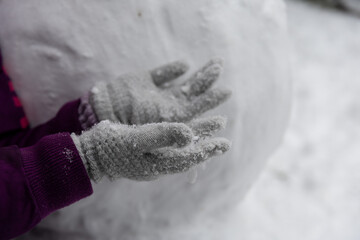 dziecięce rękawiczki pokryte śniegiem. w tle bałwan © workszop