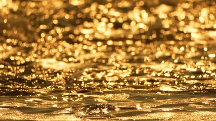 Golden water ocean waves sparkling light on sandy beach at sunset, beautiful nature background - Powered by Adobe