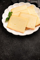 Raclette cheese portion slicing natural product tasty snack fresh delicious gourmet food background on the table rustic top view copy space