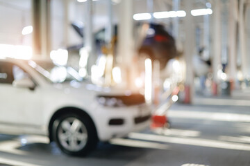 Blurred interior of a modern auto repair shop with cars and equipment