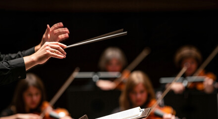 Conductor with enthusiasm leading an orchestra on dark background 
