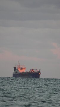 Ship ocean dredging vessel floats slowly on the horizon during a beautiful dramatic cloudy sunset or sunrise